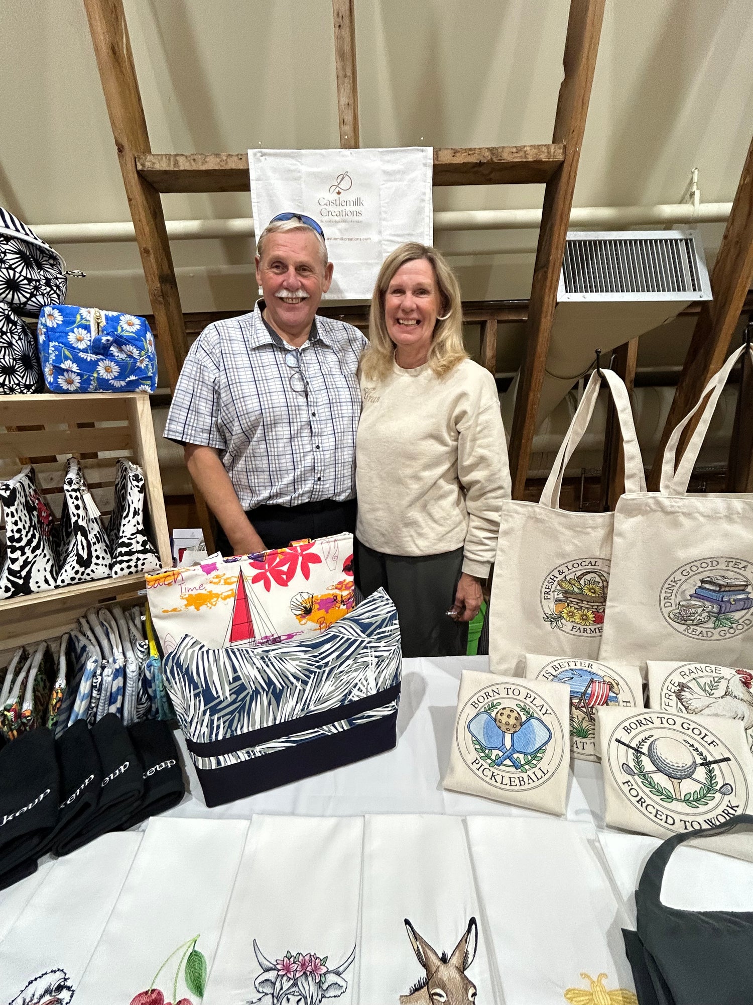Evelyn Stewart and Alfred Saunders, owners of Castlemilk Creations organizing embroidered products and personalized items on a table