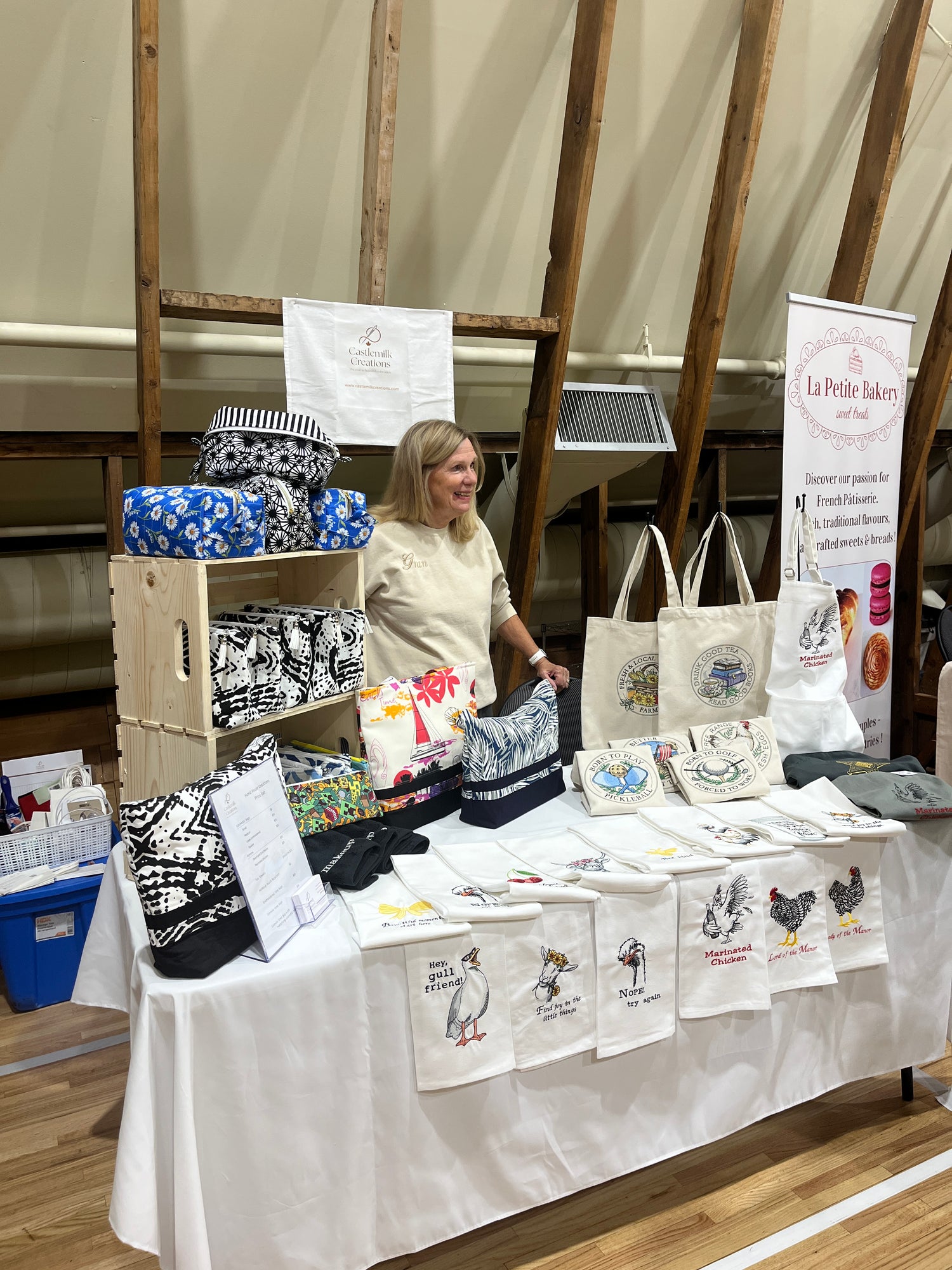 Evelyn Stewart, owner of Castlemilk Creations organizing embroidered products and personalized items on a table