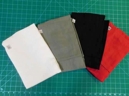 Four fabric swatches in white, gray, black, and red for embroidered aprons in Calgary