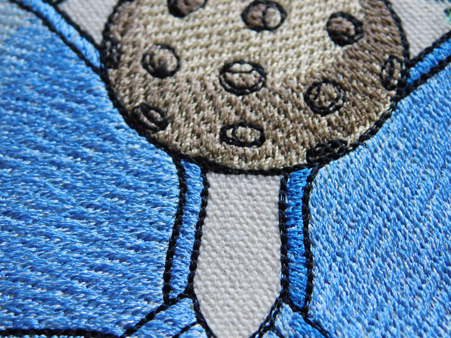 Close-up of a handmade embroidery of pickleball on a blue embroidered paddle board