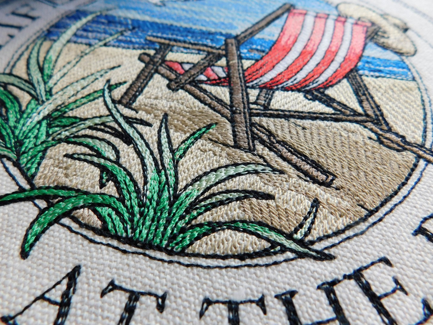 Embroidery of a beach scene with a red striped beach chair, grass, and text on 100% cotton tote bag..