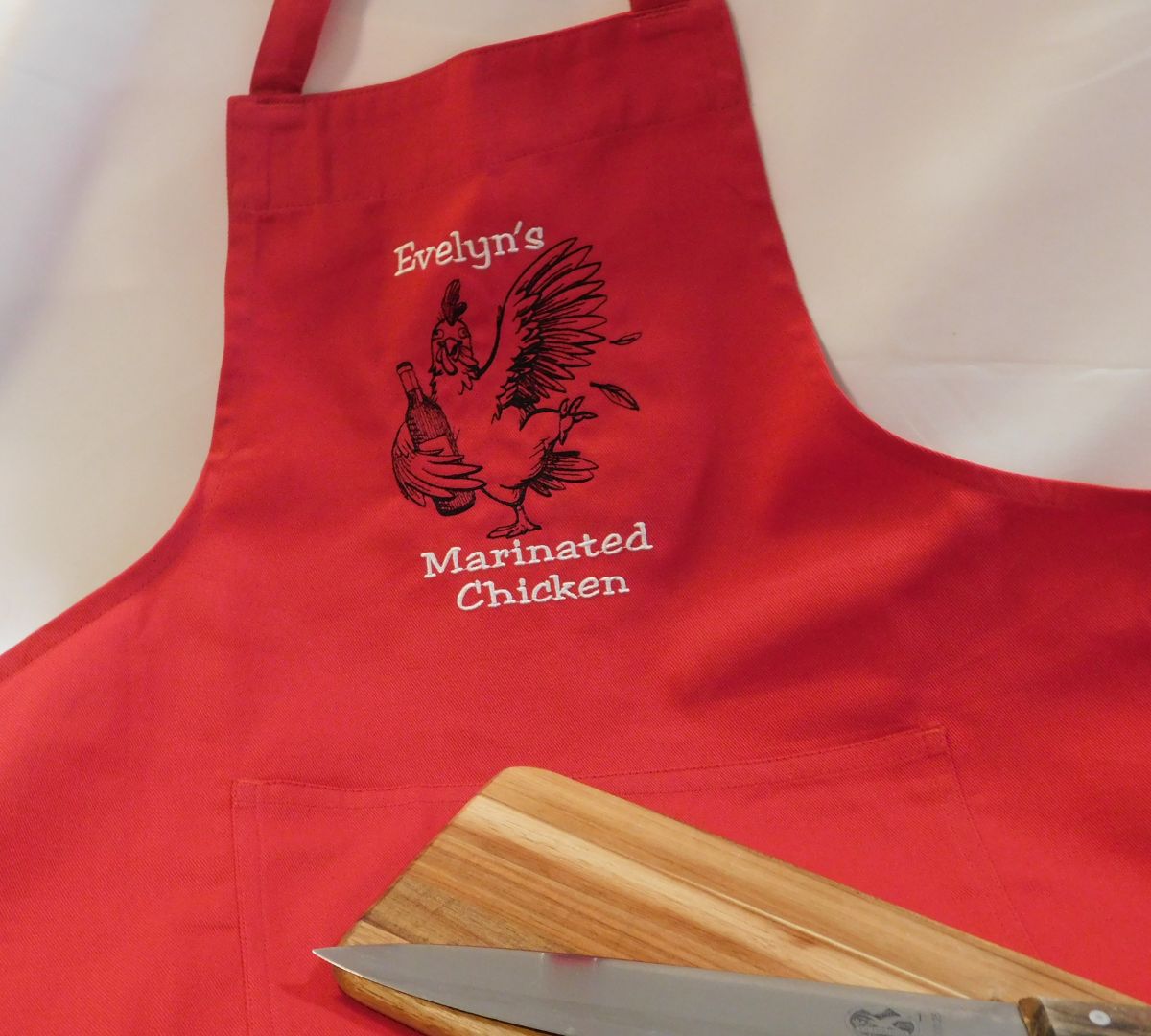 Embroidered Red apron in Calgary with chicken graphic and text on a white background